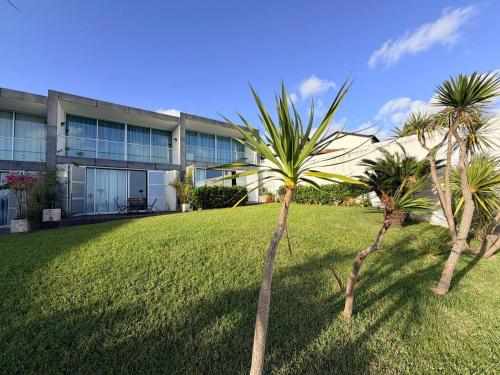 two palm trees in front of a building at Marina Mar II - Moradia T3 in Vila Franca do Campo