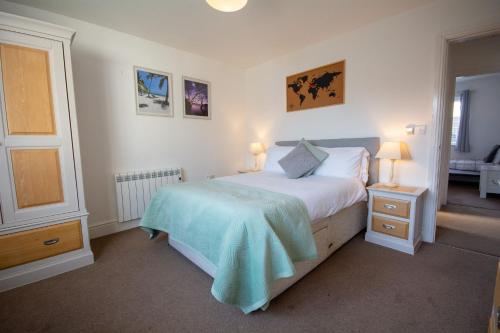 a bedroom with a bed with a blue blanket on it at Pine Cones in Rhoscolyn