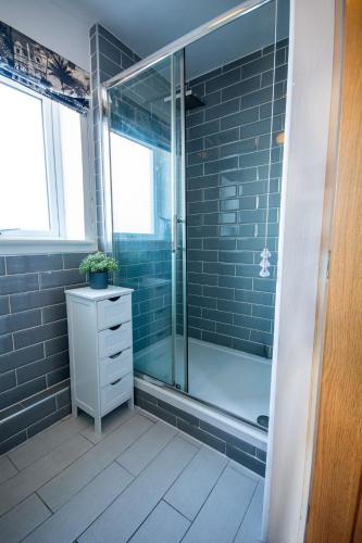 a bathroom with a glass shower and a sink at Pine Cones in Rhoscolyn