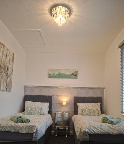 a bedroom with two beds and a chandelier at 5 Sea Spray in Burnham on Sea