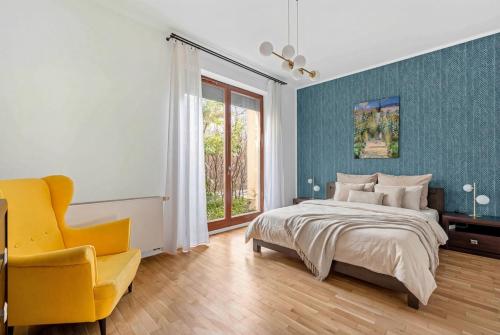 a bedroom with a bed and a yellow chair at Wilanów Cinema Apartment in Warsaw