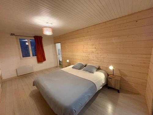 a bedroom with a large bed in a wooden wall at Appartement la Tûte centre Laruns in Laruns