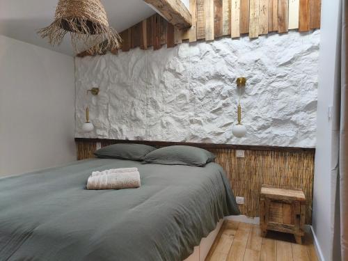 a bedroom with a large bed and a stone wall at Escale à Clisson - Les jardins de Bali in Clisson