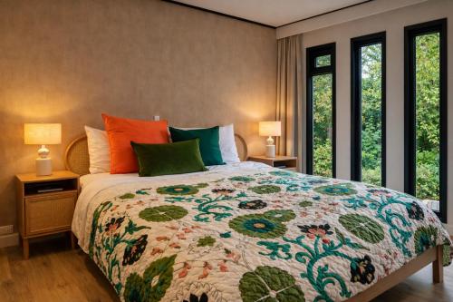a bedroom with a bed with a colorful quilt at StayatSas Pippa grote omheinde tuin in het bos aan grote vijver, zwembad en restaurant op het park, stijlvol ingericht,veel privacy in Doornspijk