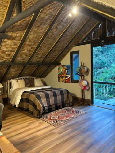a bedroom with a bed and a wooden floor at Chalé - Refúgio Serra das Águas in Araras Petropolis