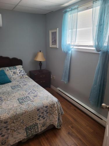 a bedroom with a bed and a window with blue curtains at Nice and cozy in Dalhousie
