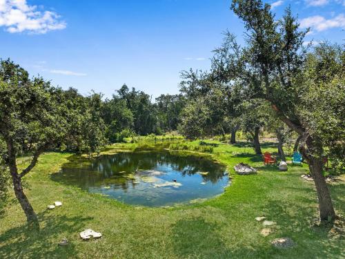 a pond in the middle of a field with trees at Windmill Ranch - Terra Casita #2 in Wimberley