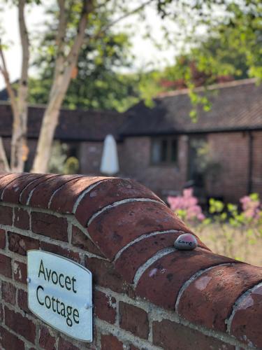 a brick wall with a sign that reads suggest coffee at Avocet Cottage in Dunwich