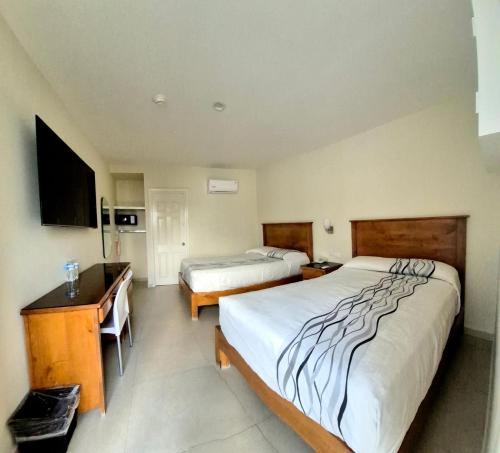 a hotel room with two beds and a desk at Hotel Baja in Tijuana