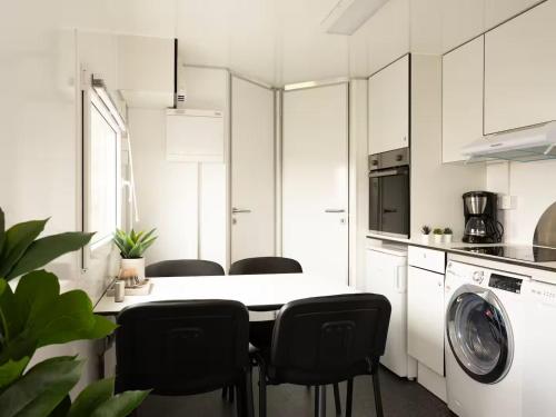 a white kitchen with a table and black chairs at Budget Mobile House in Faroe Islands in Strendur
