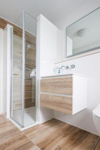 een witte badkamer met een douche en een wastafel bij Appartementen de Strandloper in Bergen aan Zee