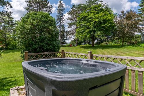 a hot tub in a garden next to a fence at La Vieille École & Spa & Parc Naturel in West Brome