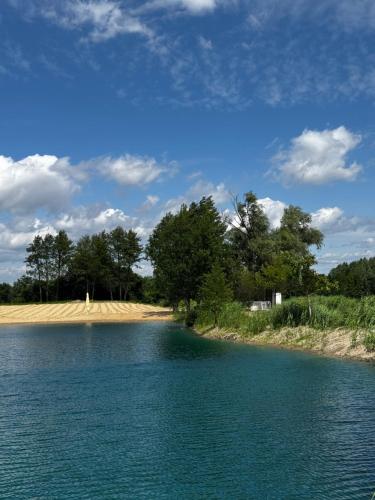 ein großes Gewässer mit Bäumen und einem Strand in der Unterkunft Wake Villa in Brwinów