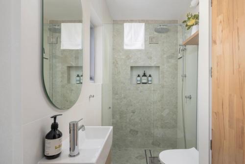 a bathroom with a shower and a sink and a mirror at Sundeck Shoal Bay Ground floor with views and pool access in Shoal Bay