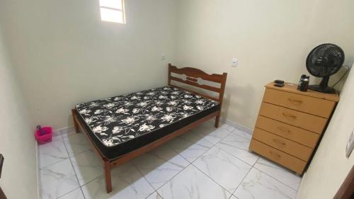 a small bedroom with a bed and a dresser at Casa Aconchego in Japaratinga