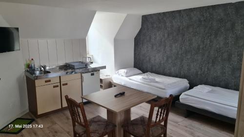 a small room with a table and a bed and a kitchen at My Pension City Stadtbergen Augsburg in Stadtbergen