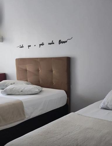 a bedroom with two beds and a sign on the wall at Hotel Entre Lagos in São José do Cerrito
