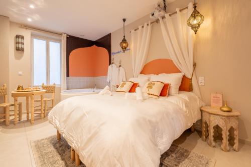 a bedroom with a large white bed and a bathroom at Marrakech Cinéma Jacuzzi - Suite romantique in Feyzin