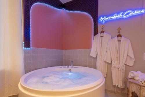a bathroom with a tub with a sign on the wall at Marrakech Cinéma Jacuzzi - Suite romantique in Feyzin