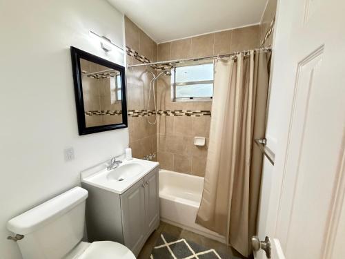 a bathroom with a toilet and a sink and a shower at Bek's Hostel in Hallandale Beach