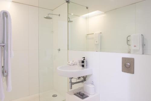 a white bathroom with a sink and a shower at Tavira Convent, 2-bedroom, condo, pool in Tavira