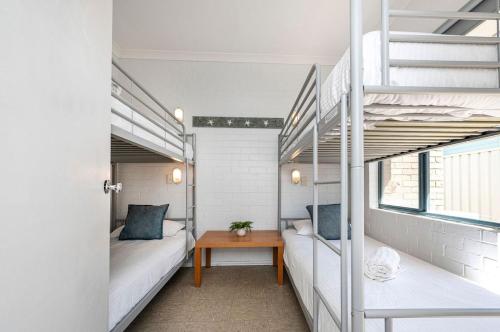 a room with two bunk beds and a table at Windsurfer Beach Chalet 4 in Lancelin