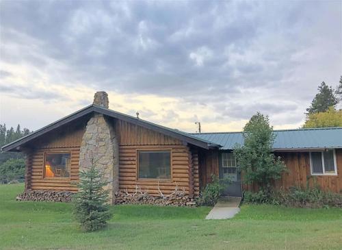 a log cabin in the middle of a field at 12 Mile Ranch in Custer