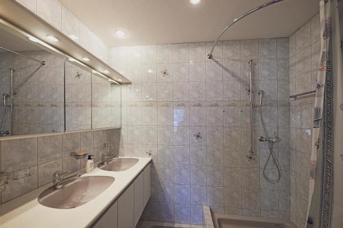 a bathroom with two sinks and a shower at Gemütliche Ferienwohnung in Ladir bei Flims Laax in Ilanz