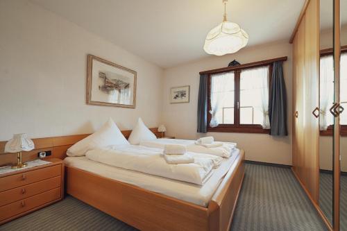 a bedroom with a large bed with white sheets at Gemütliche Ferienwohnung in Ladir bei Flims Laax in Ilanz