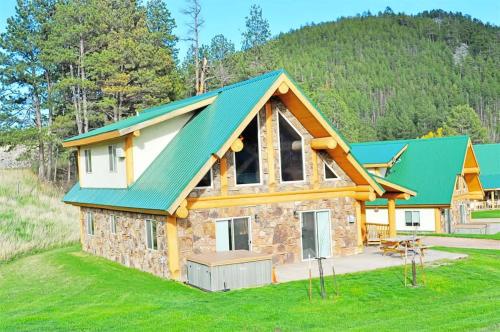 a house with a green roof on a grass field at Cottage at Storm Mountain #5 in Hill City