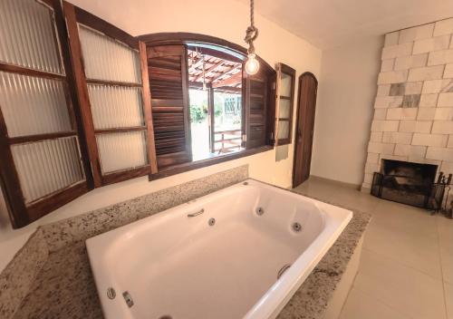 a large white tub in a bathroom with a window at Pousada Flor de Penedo in Penedo