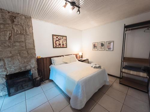 a bedroom with a bed and a stone wall at Pousada Flor de Penedo in Penedo