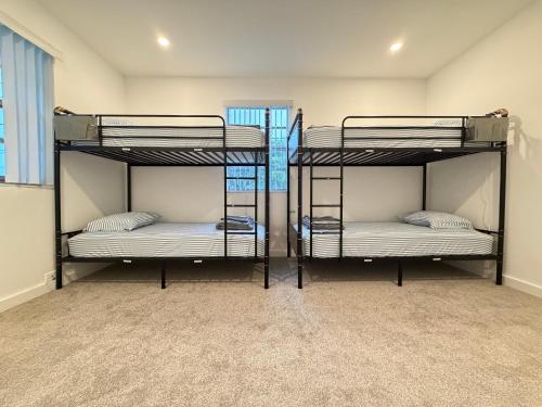 three bunk beds in a room with a window at Bek's Hostel in Hallandale Beach