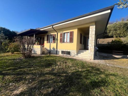 a small yellow house with a grass yard at Villa Cà Bottura agli ulivi in Bardolino