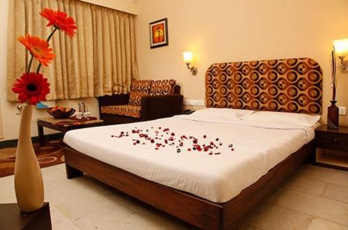 a bedroom with a bed with red flowers on it at Hotel Vales Park in Dindigul
