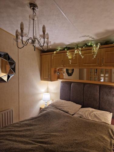 a bedroom with a bed and a chandelier at BELLESVIEW Clarach Bay in Aberystwyth