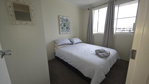 a bedroom with a white bed with a window at Crystal Waters 7 Ocean Corridor Views, Restaurants, Town Centre in Forster