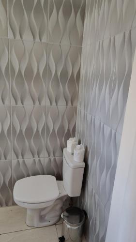 a bathroom with a toilet and a tiled wall at casarosaencantada -villaencantorosa in Gramado
