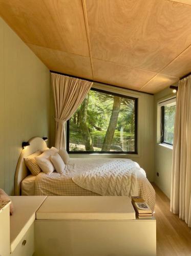 a bedroom with a bed and a large window at The Flower Sanctuary Tiny Home in Springbrook