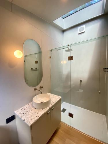 a bathroom with a sink and a glass shower at The Flower Sanctuary Tiny Home in Springbrook