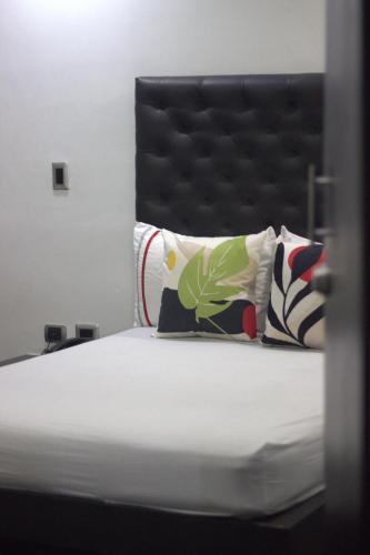 a bedroom with a bed with a black headboard and pillows at Hotel Panorama Urban Medellin in Medellín