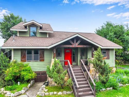 a green house with a red door at Clutter Falls Retreat - Main House in New Braunfels