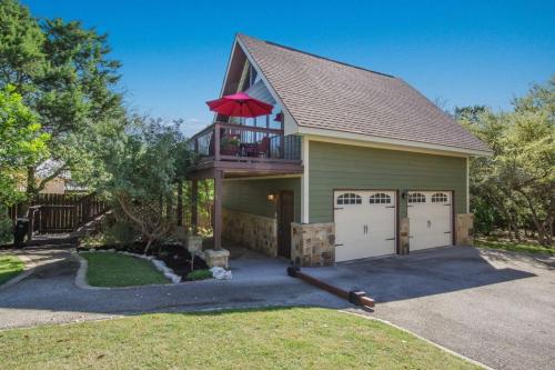 a house with a balcony and a deck with two garage doors at Clutter Falls Retreat - Guest House in New Braunfels