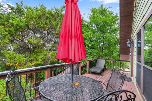a table with a red umbrella on a balcony at Clutter Falls Retreat - Guest House in New Braunfels