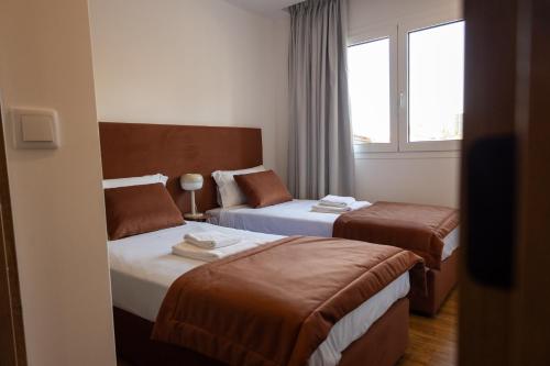a hotel room with two beds and a window at Trio Living Residences in Vila Real