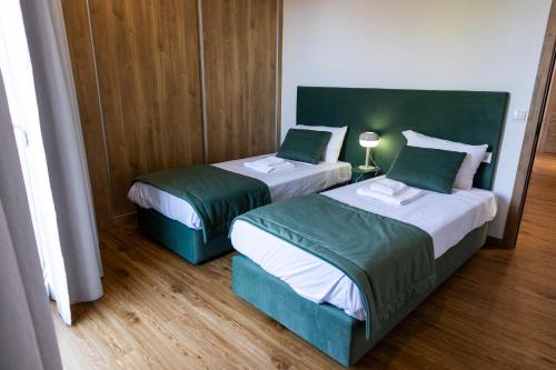 a room with two beds with green and white at Trio Living Residences in Vila Real