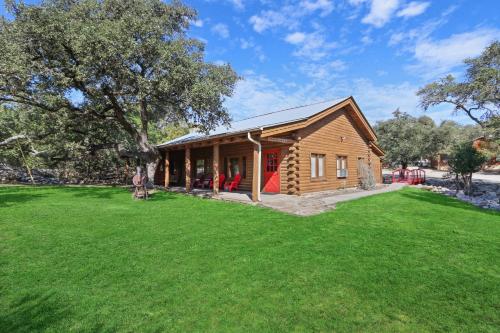 a log cabin with a green lawn in front of it at Wimberley Log Cabins Resort and Suites- Unit 3 in Wimberley