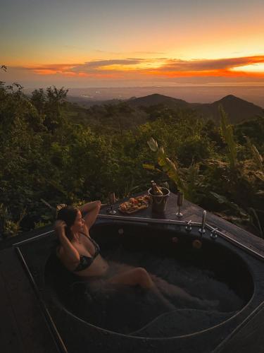 a woman sitting in a bath tub at sunset at Domos Mirador Romantic Private Honeymoon Glamping in Miramar