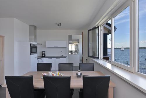 une salle à manger avec une table et des chaises et l'océan dans l'établissement Penthouse XL Veerse Meer, à Kamperland