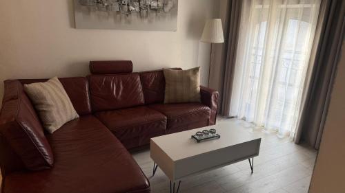a living room with a brown leather couch and a coffee table at Appartement cosy entièrement équipé in Villeneuve-sur-Lot